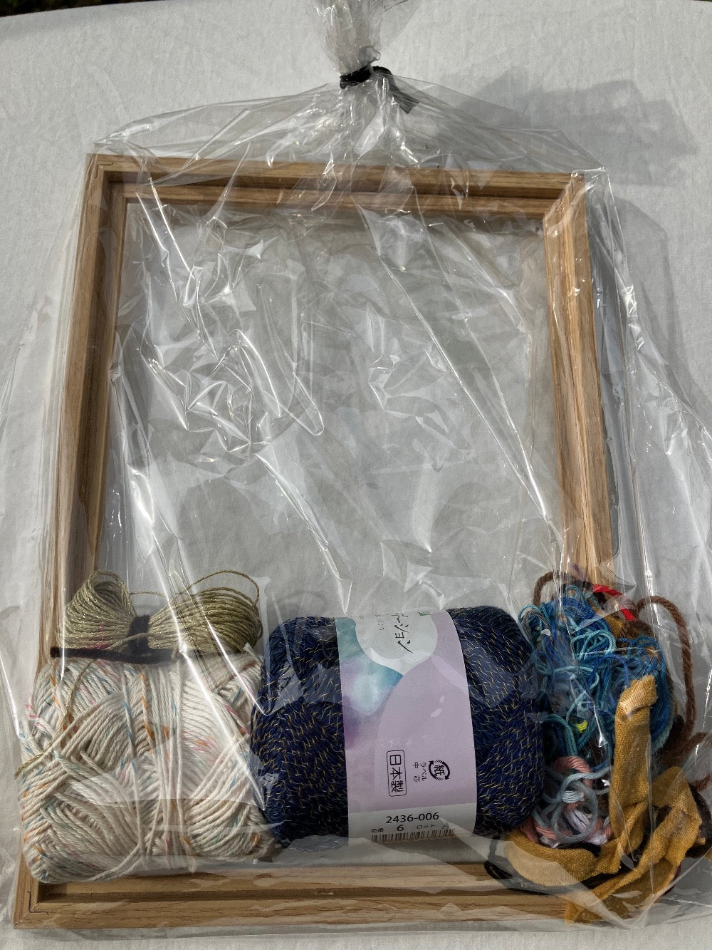 Plastic wrapped weaving kit with colorful yarn, and wooden frame