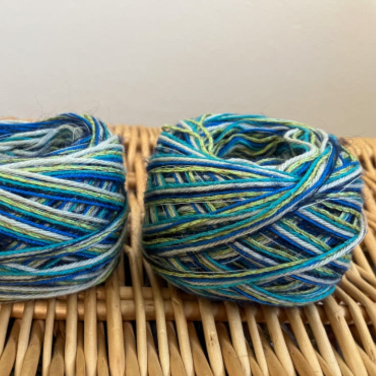 two balls of blue+green+yellow mixed fiber yarn