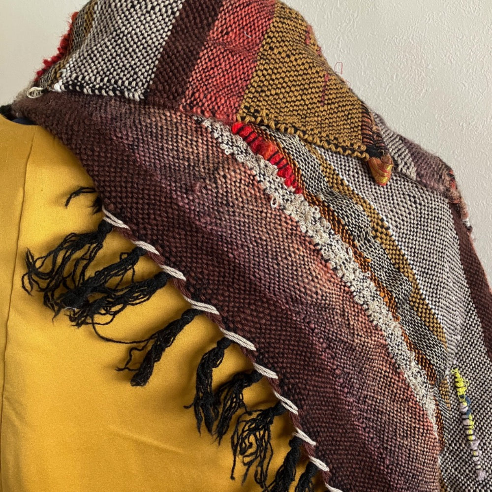 Zoom-in of brown and orange section of shawl scarf and of white and black hemmed fringe