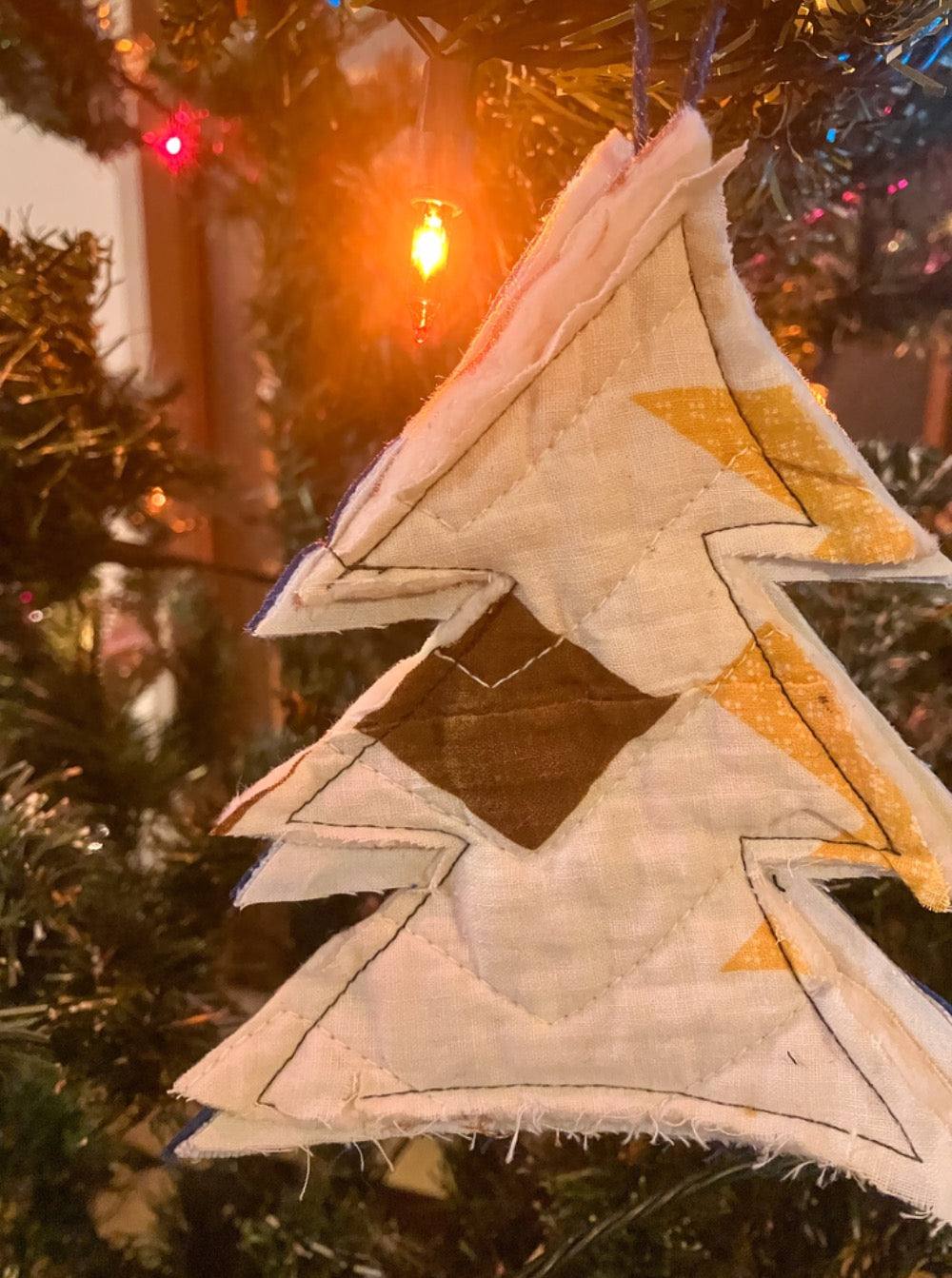 Quilted tree hanging on Christmas tree with Christmas lights