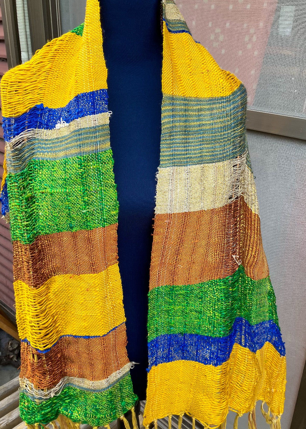 Vivid blue, yellow, copper, and green scarf on blue mannequin