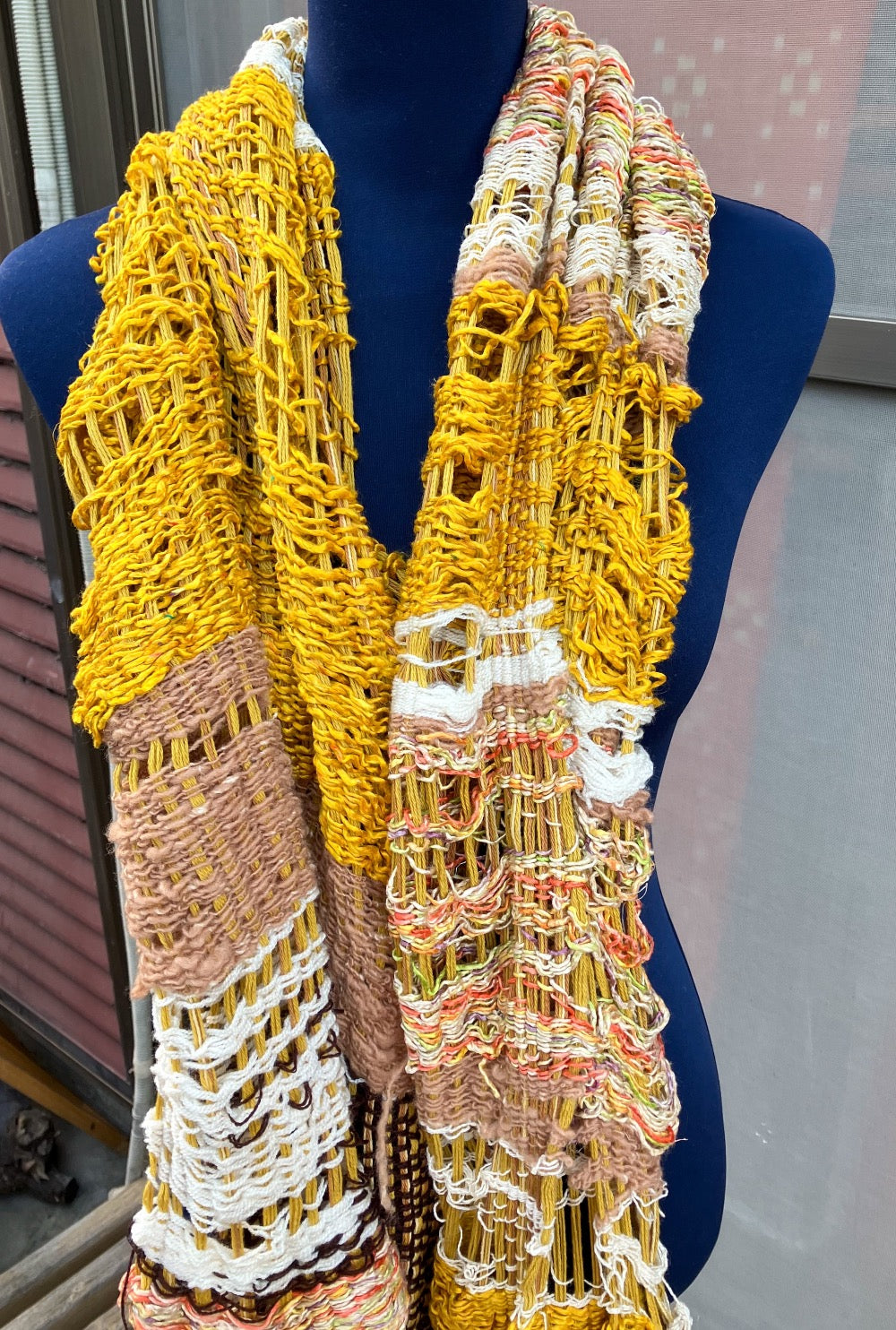 Lacey gold, brown, white, and variegated scarf on blue mannequin