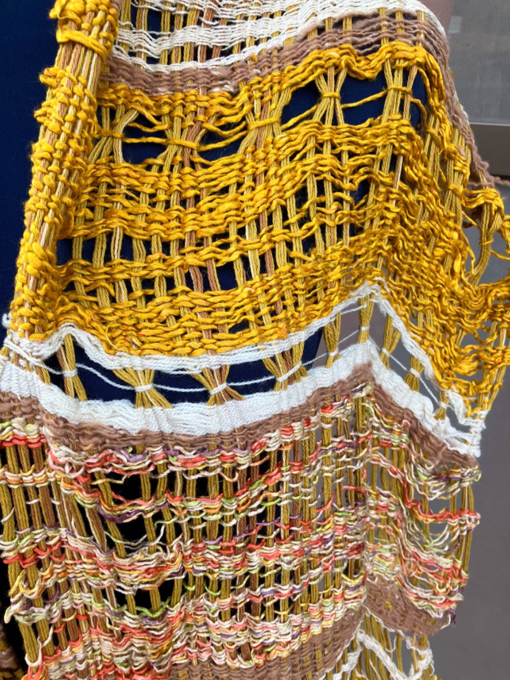 Lacey gold, brown, white, and variegated scarf on blue mannequin