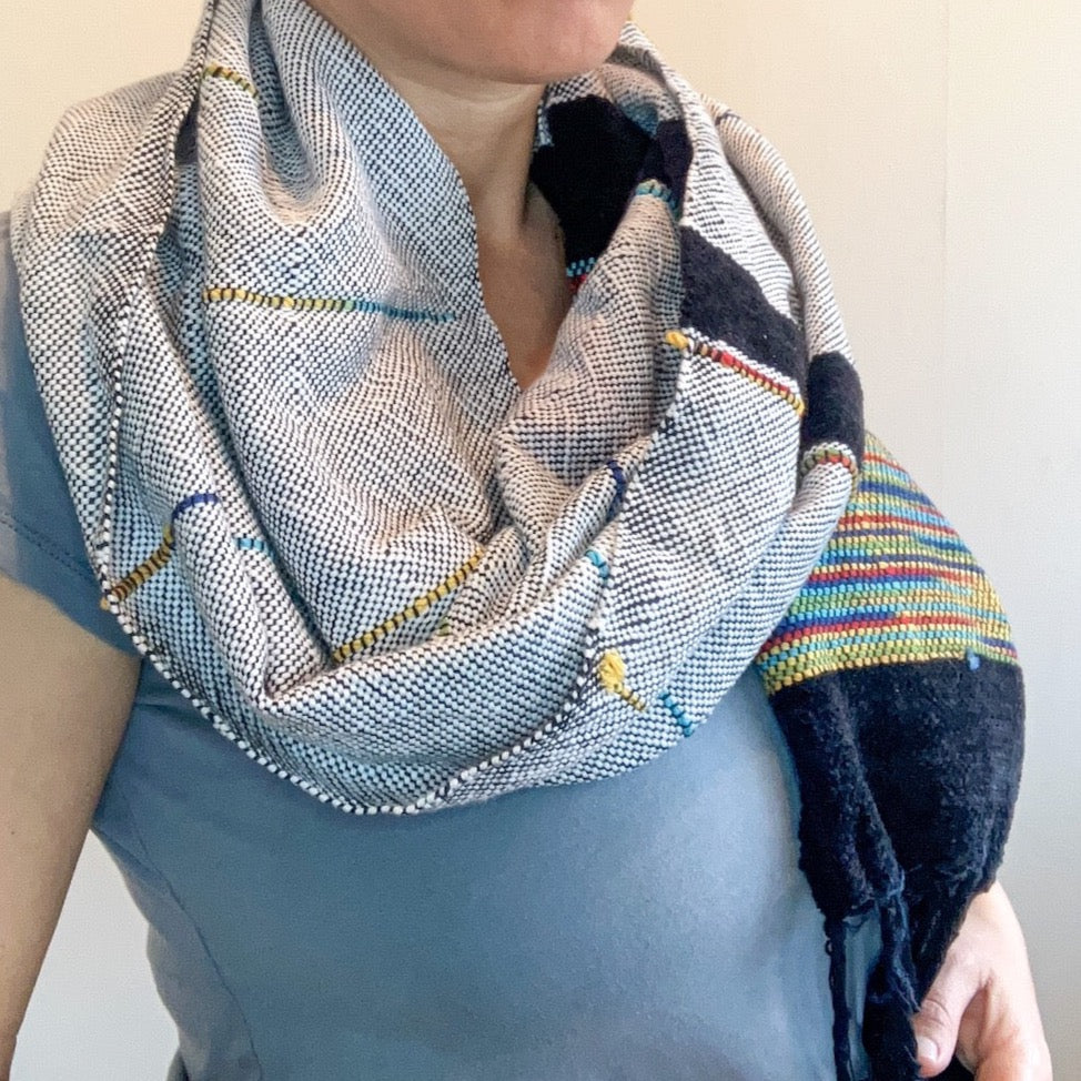 Female model wearing black and white shawl with multicolor accents and side. There are two blocks of velvety black yarn accents.