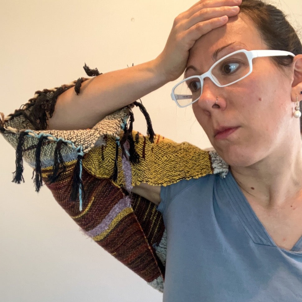 Female model with hand on head showing fringed sleeve of brown and yellow shrug