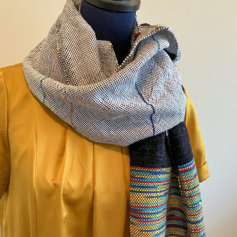 Female mannequin wearing black and white shawl with multicolor accents and side. There are two blocks of velvety black yarn accents.