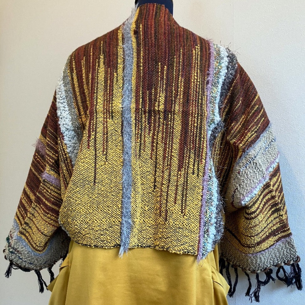 Back side of brown and gold shrug on back of mannequin wearing a gold dress