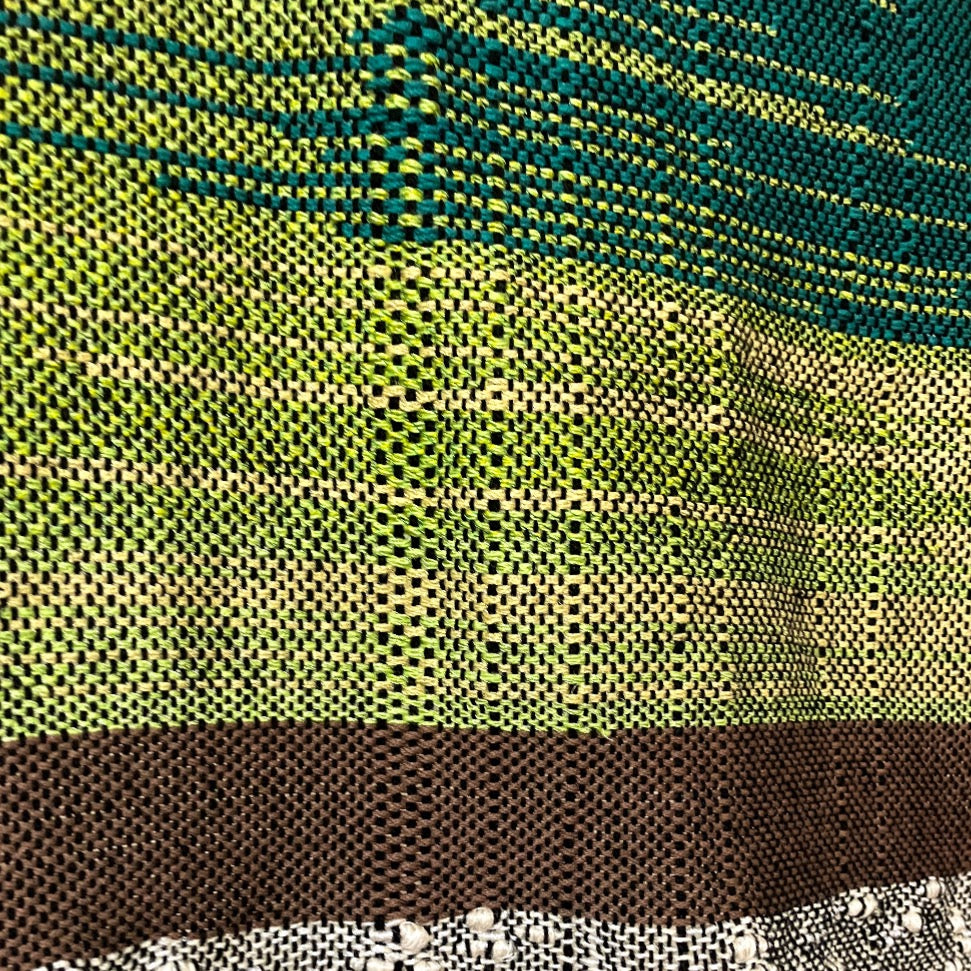 Upclose detail of green and brown yarn on panel