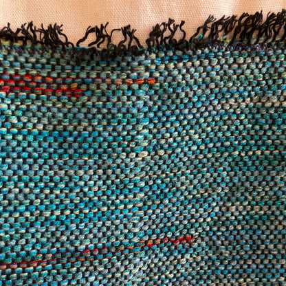 Close up of blue-green and red cotton on beige bag