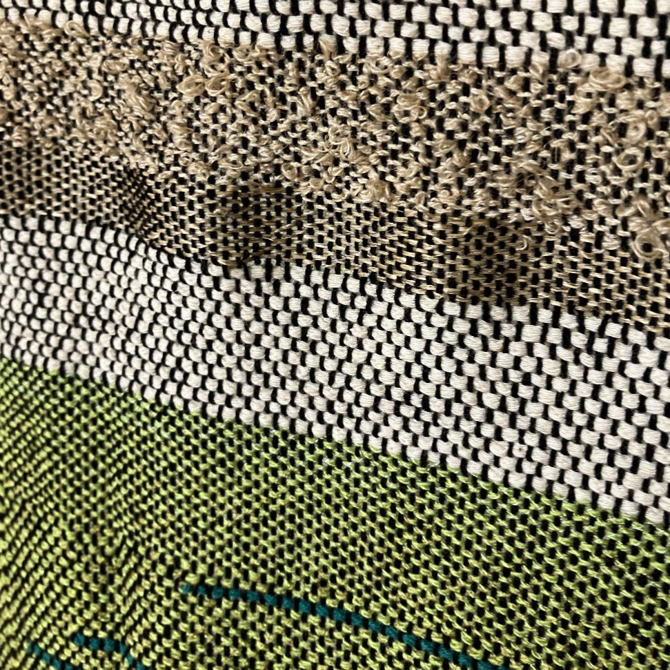 Upclose detail of textured tan and green yarn on panel