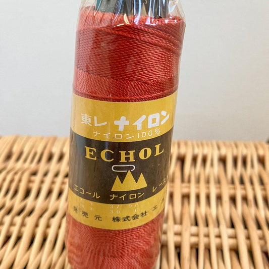 One cone of orange nylon yarn in plastic wrap with Japanese label