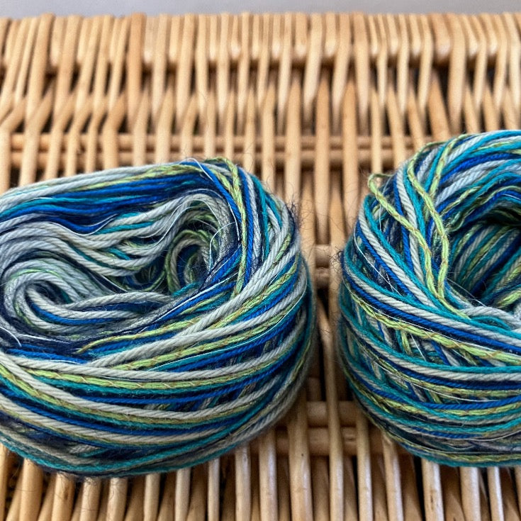 two balls of blue+green+yellow mixed fiber yarn