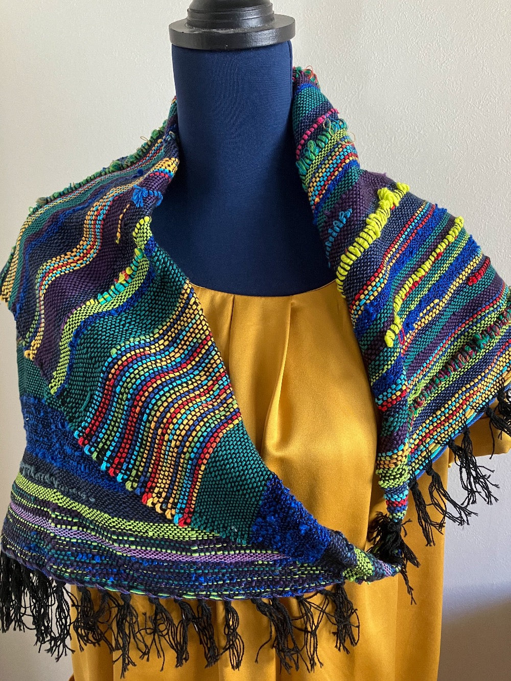 Multi colored shawl scarf on mannequin dressed in gold