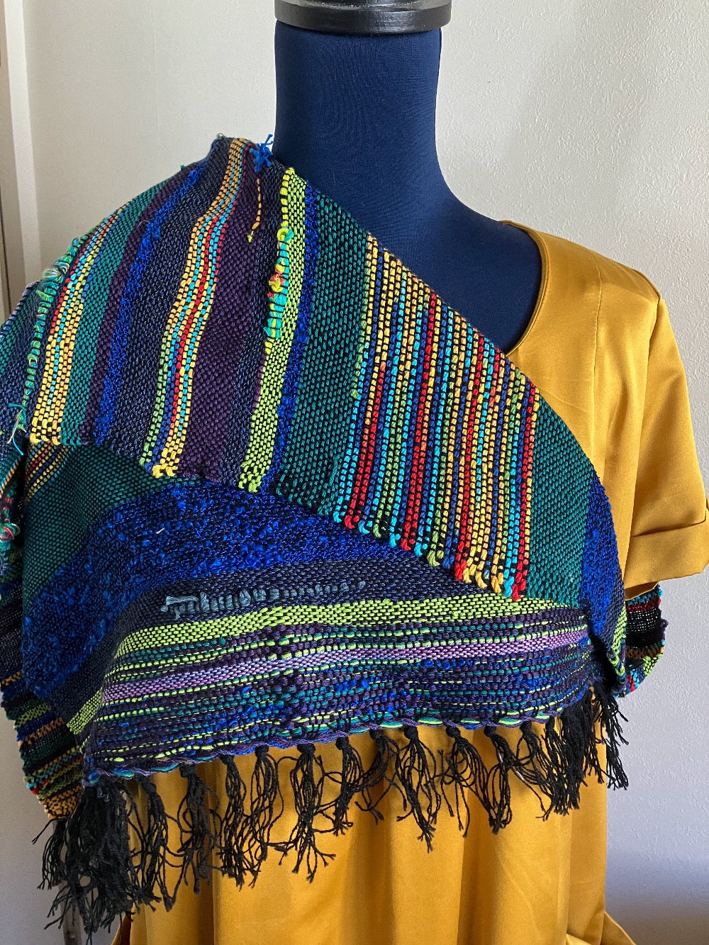 Alternative way to wear neon and jewel tones shawl scarf over one shoulder, on mannequin dressed in gold