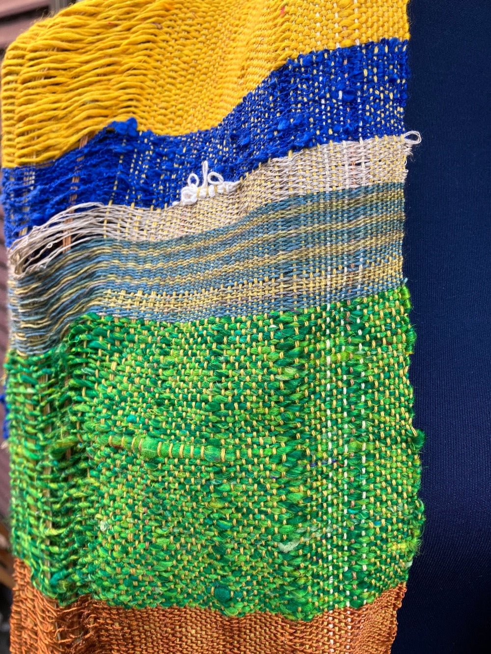 Vivid blue, yellow, copper, and green scarf on blue mannequin
