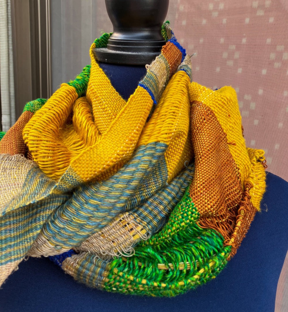 Vivid blue, yellow, copper, and green scarf on blue mannequin