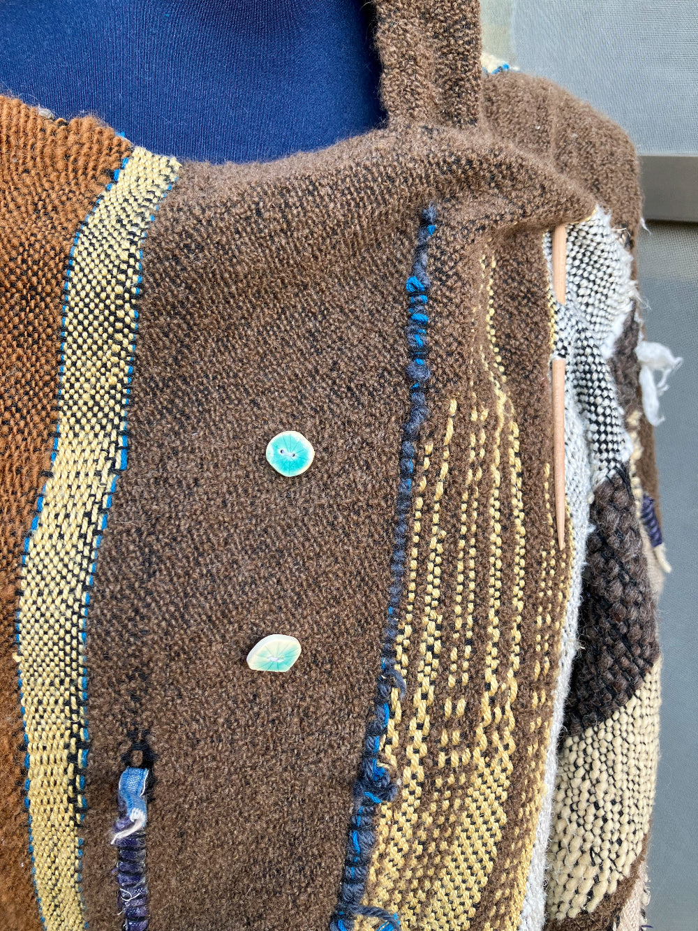 closeup of brown shawl and blue buttons