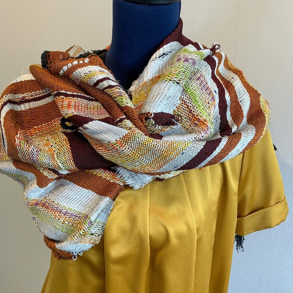 Female mannequin in gold dress wearing brown and cream silk shawl wrapped as scarf around neck