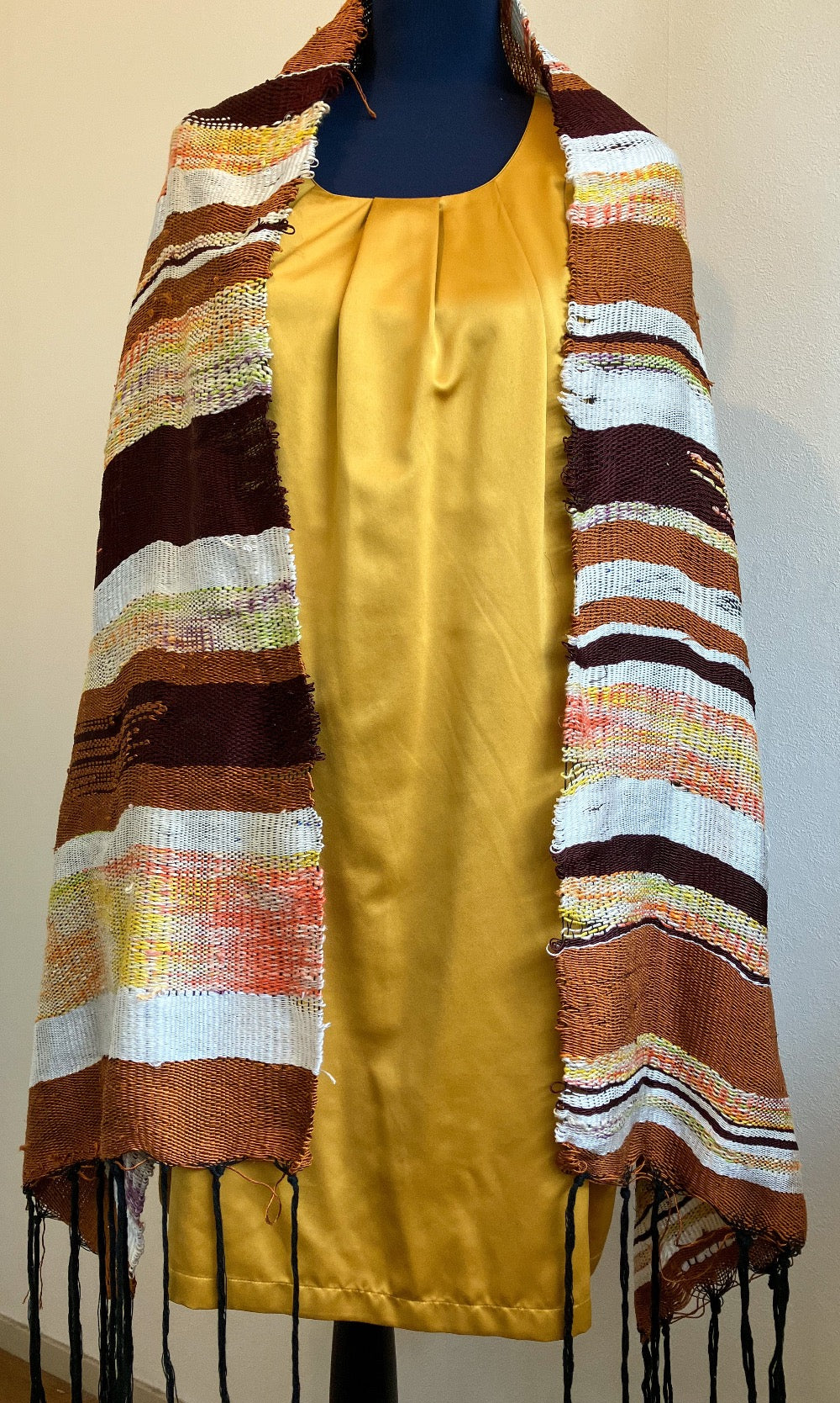 Female mannequin in gold dress wearing brown and cream silk shawl draped over shoulders
