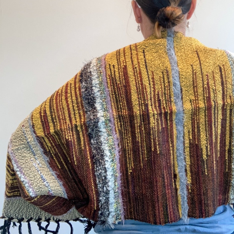 Back view of female model wearing brown and yellow shrug